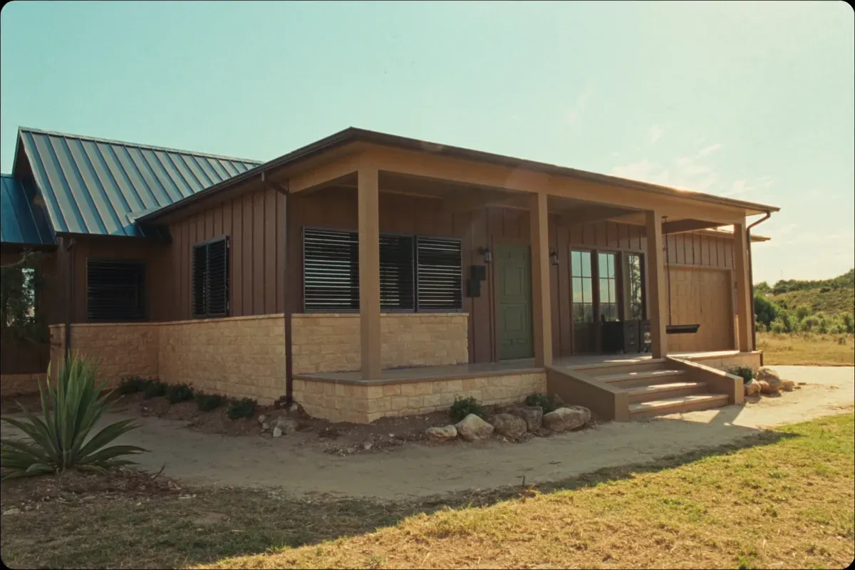 A Hill Country barndominium ranch home with limestone wainscot and a metal roof
